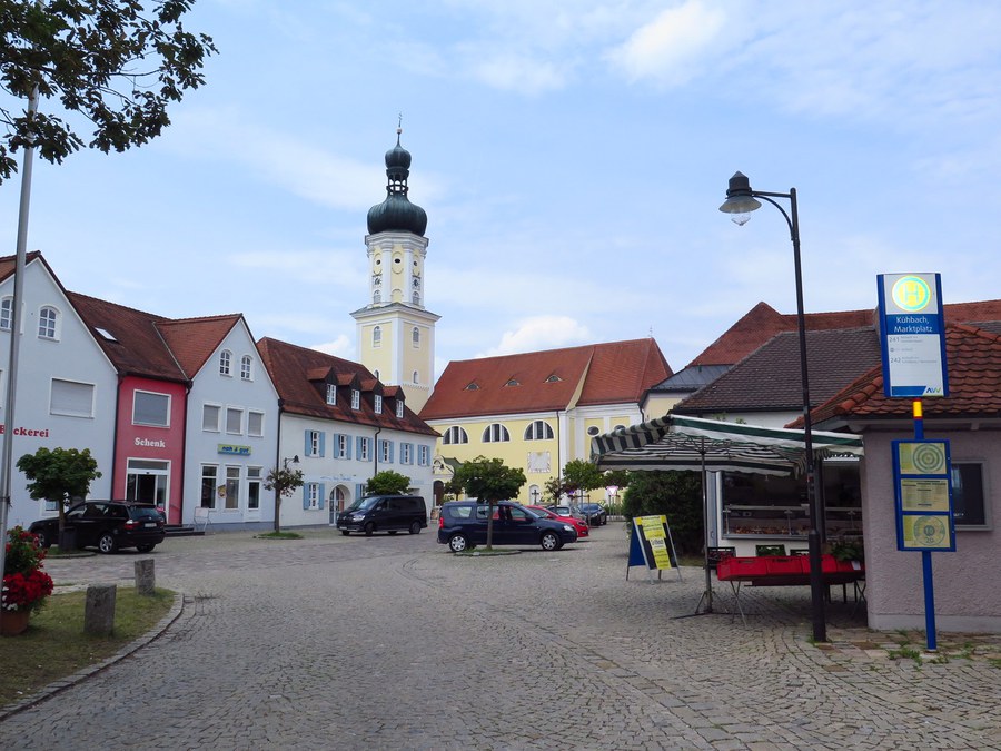 Marktplatz in Kühbach mit Blick auf die Kirche. Die Stände des Wochenmarktes sind aufgebaut.