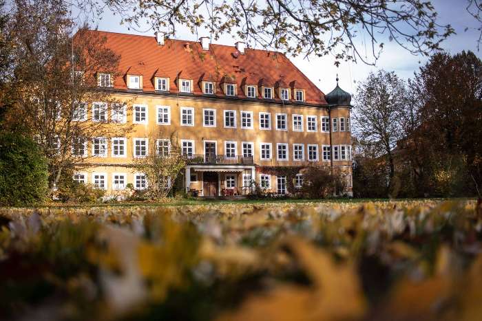 Schloss Blumenthal bei Herbst. Die Wiese vor dem Gebäude ist bedekct mit Laub.